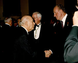 Juan Carlos I saluda a uno de los invitados al acto en presencia de Víctor García de la Concha, e...