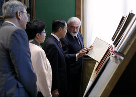 Darío Villanueva enseña un libro a Feng Qinghua, Yu Man y Lu Jingsheng de la SISU en la sala Dáma...