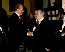 Juan Carlos I saluda a uno de los invitados al acto en presencia de Víctor García de la Concha, e...