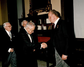 Juan Carlos I de España saluda a uno de los invitados al acto, en presencia de Gregorio Salvador ...