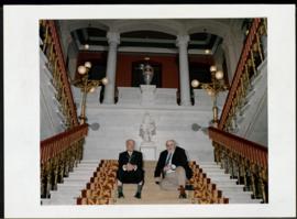 Eliseo Álvarez Arenas y Álvaro Pombo sentados en la escalera principal de la Real Academia Española